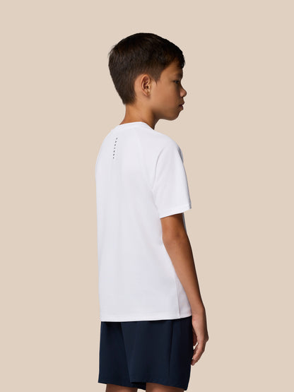 Profile view of a young boy wearing a white Junior Adapt Training T Shirt against a beige background