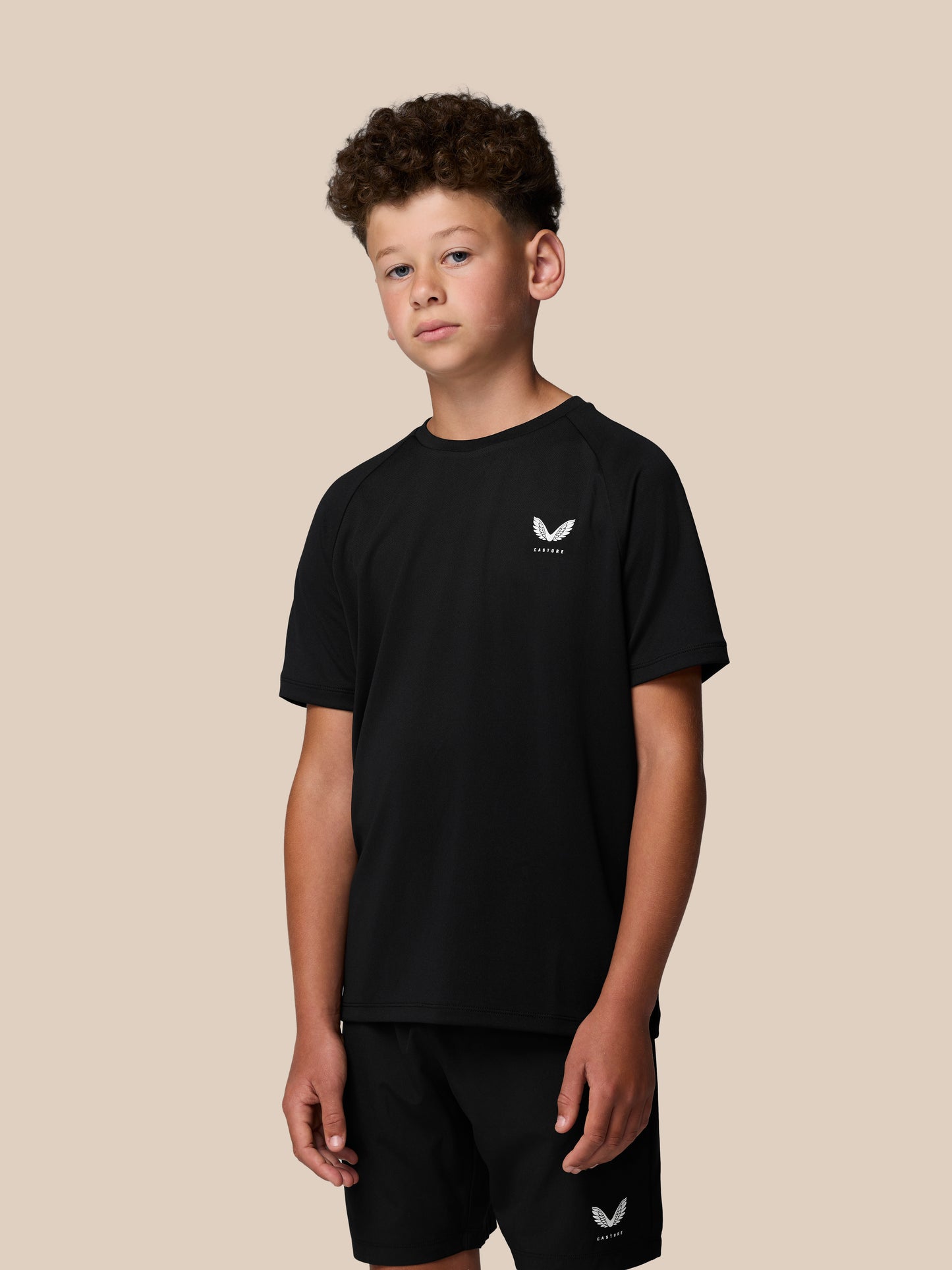 Young boy wearing black Castore Adapt T Shirt with logo on the left chest.
