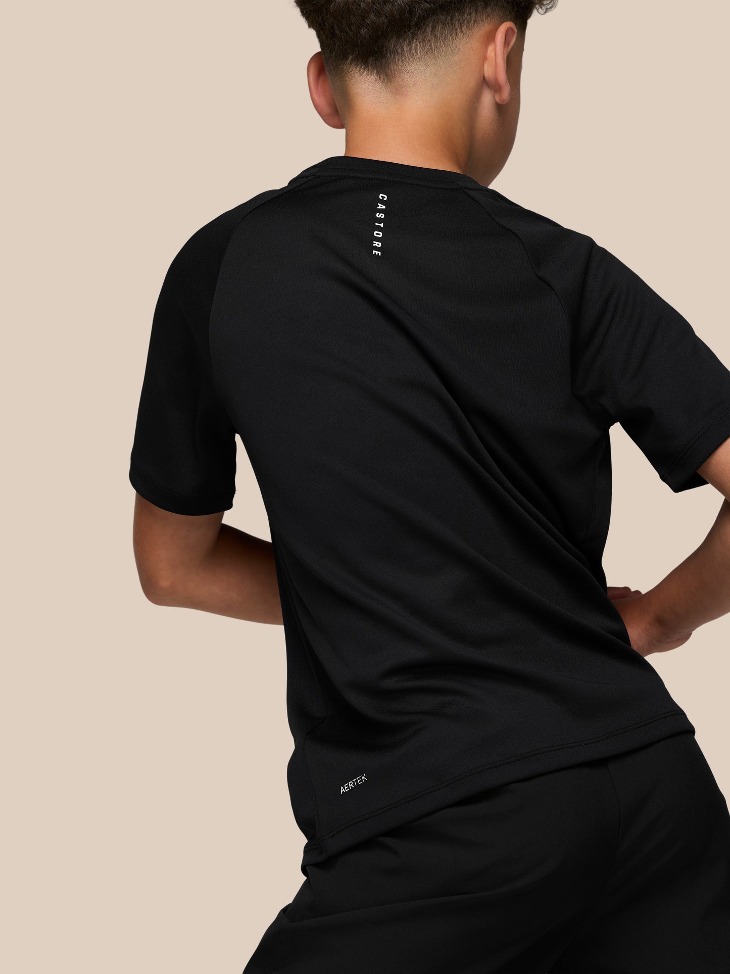 Back view of a black Castore T shirt showing a vertical Castore wordmark on the upper back