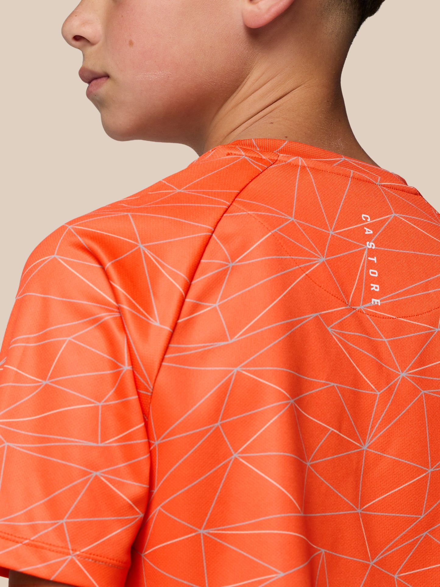 Close-up of bright orange junior short sleeve t shirt with white geometric line pattern at the shoulder and back of neck