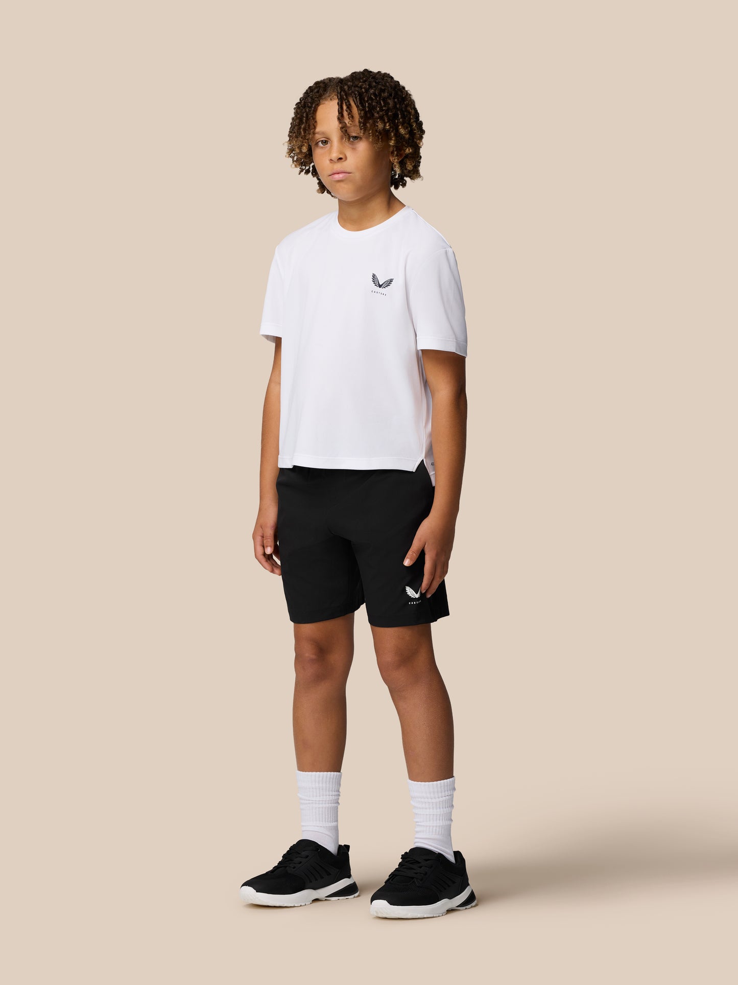 Front view of a young boy in a white Junior’s Adapt Short Sleeve T Shirt with Castore logo on the left chest