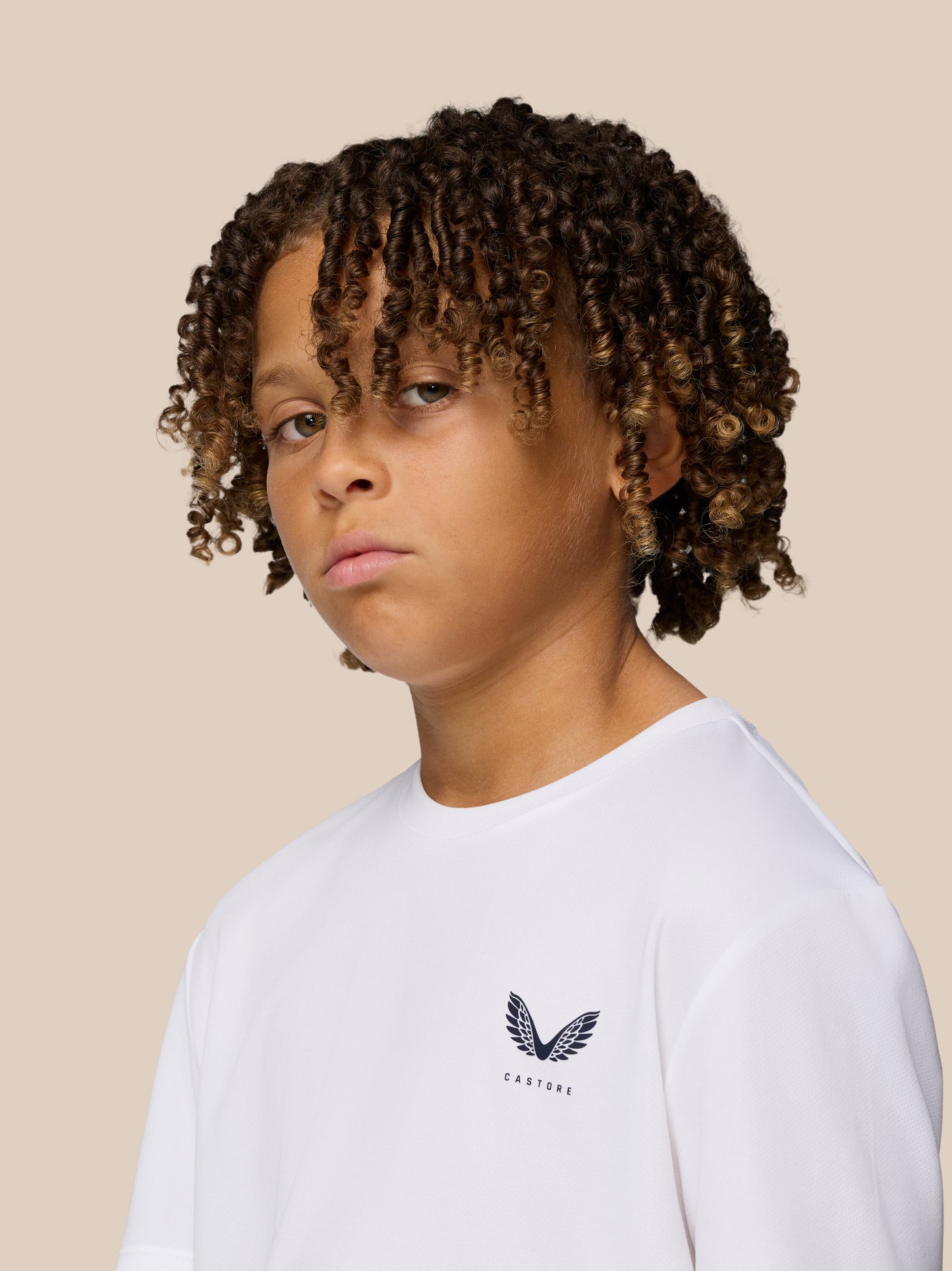 Close up of a young boy wearing a white Junior’s Adapt Short Sleeve T Shirt with Castore logo on the chest