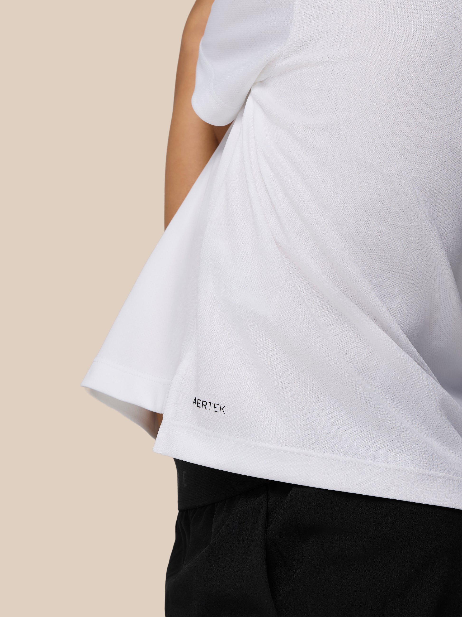 Close up of white Castore Adapt short sleeve T shirt showing textured fabric and AERTEK branding at the hem