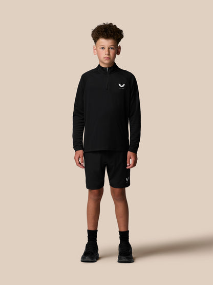 Back view of a boy in a black quarter zip showing vertical Castore branding along the upper back.