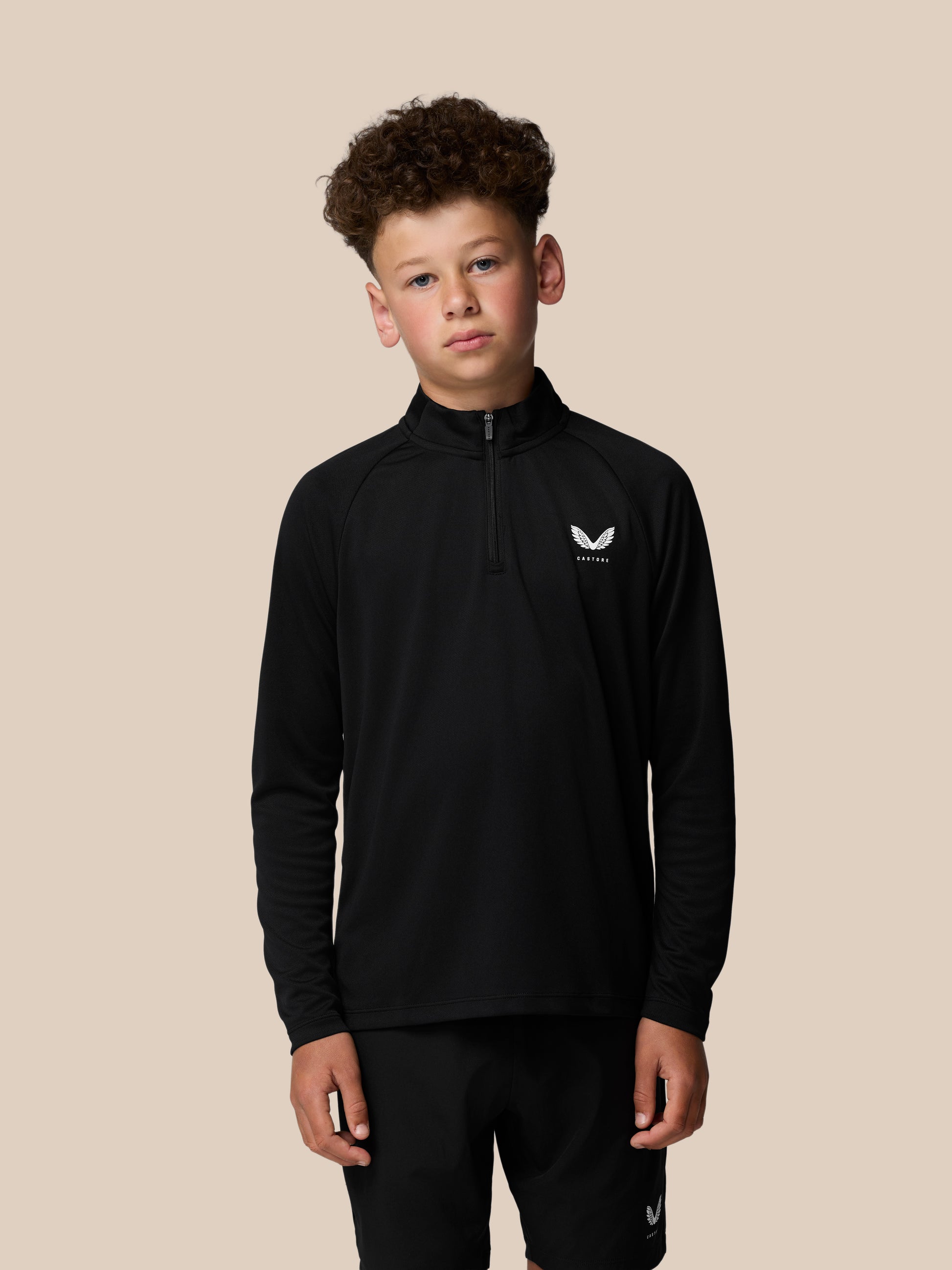 Young boy wearing a black lightweight quarter-zip with front zipper and Castore logo on the chest.