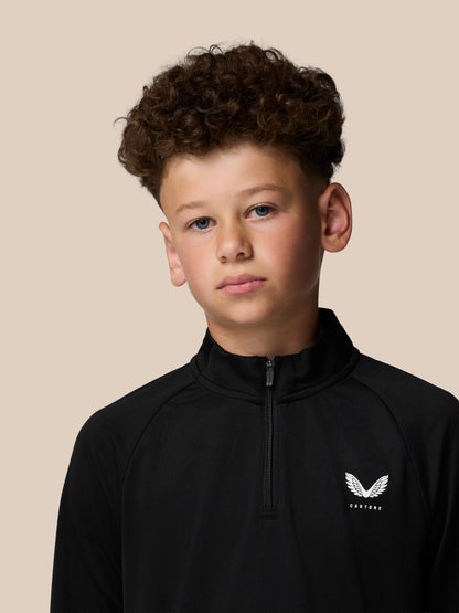 Young boy wearing a black Junior’s Adapt Lightweight Quarter Zip with front zip and Castore logo on chest
