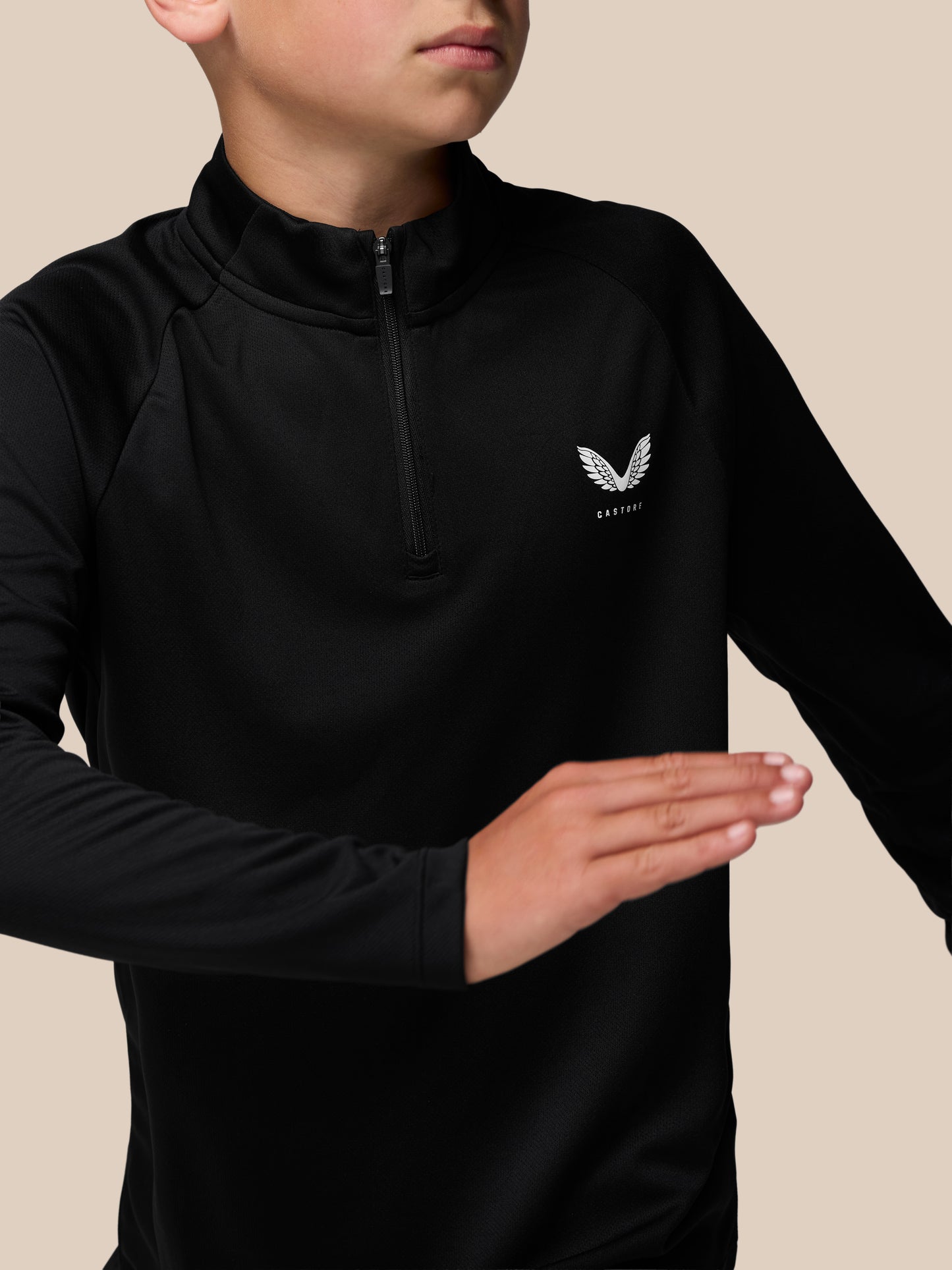 Close-up of a young model wearing a black Adapt lightweight quarter zip with center zip and Castore logo on the left chest.