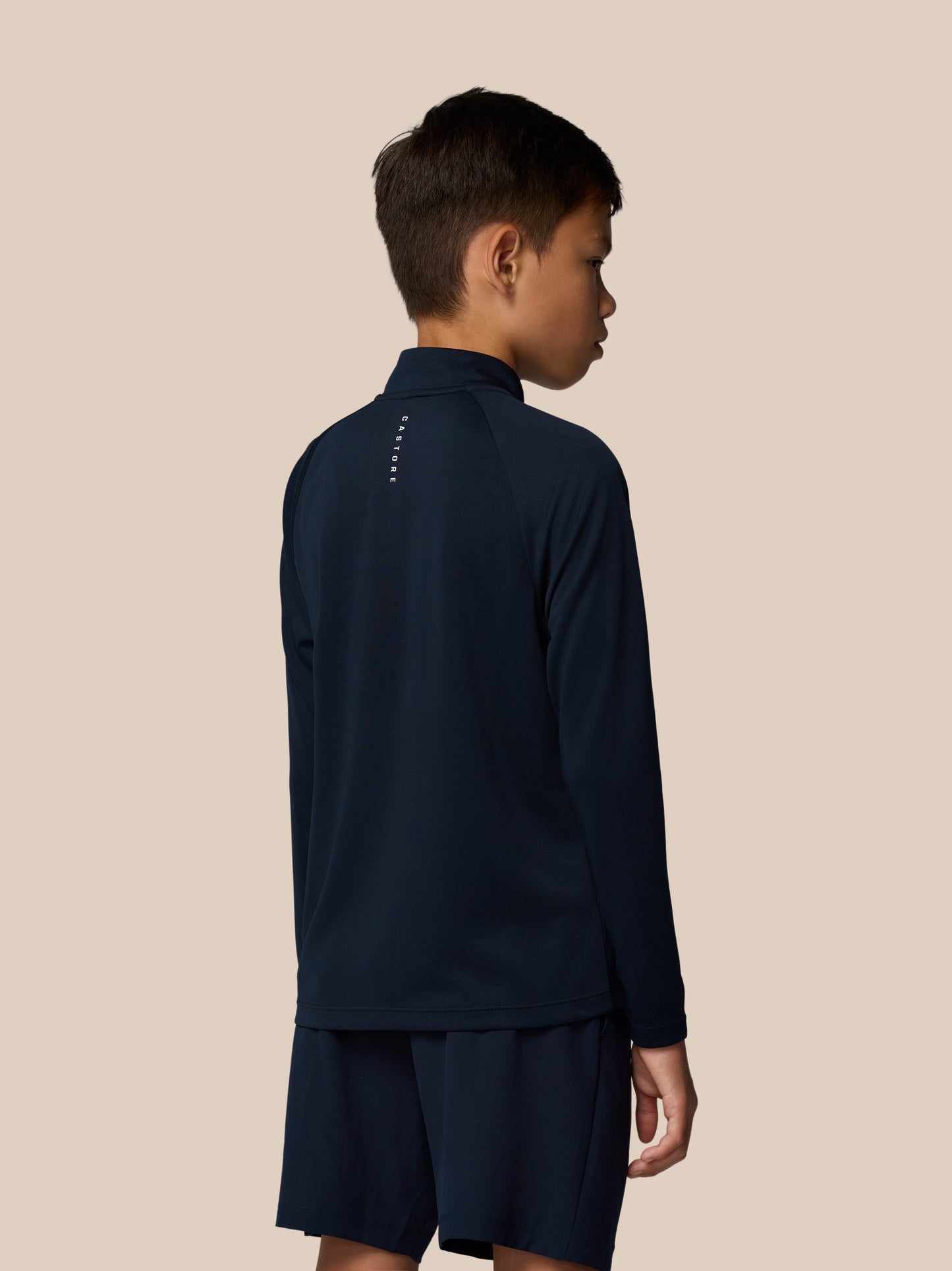 Back view of a young boy in navy Adapt Lightweight Quarter Zip showing vertical branding along the back of the neck