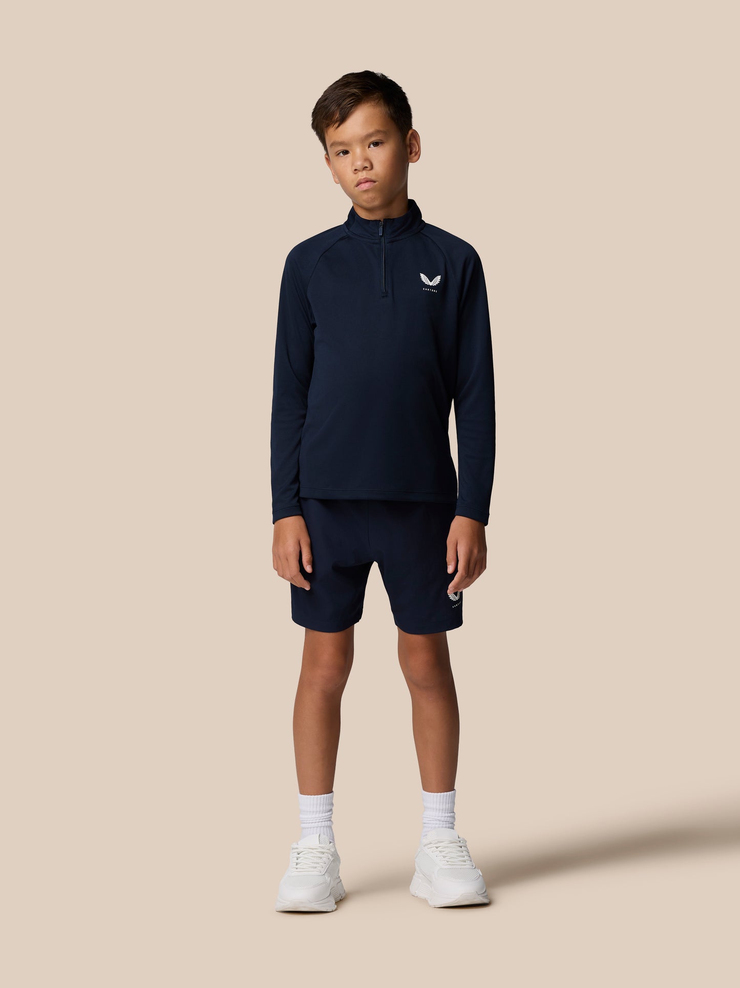 Full-body front view of a young boy in navy Adapt Lightweight Quarter Zip with matching navy shorts