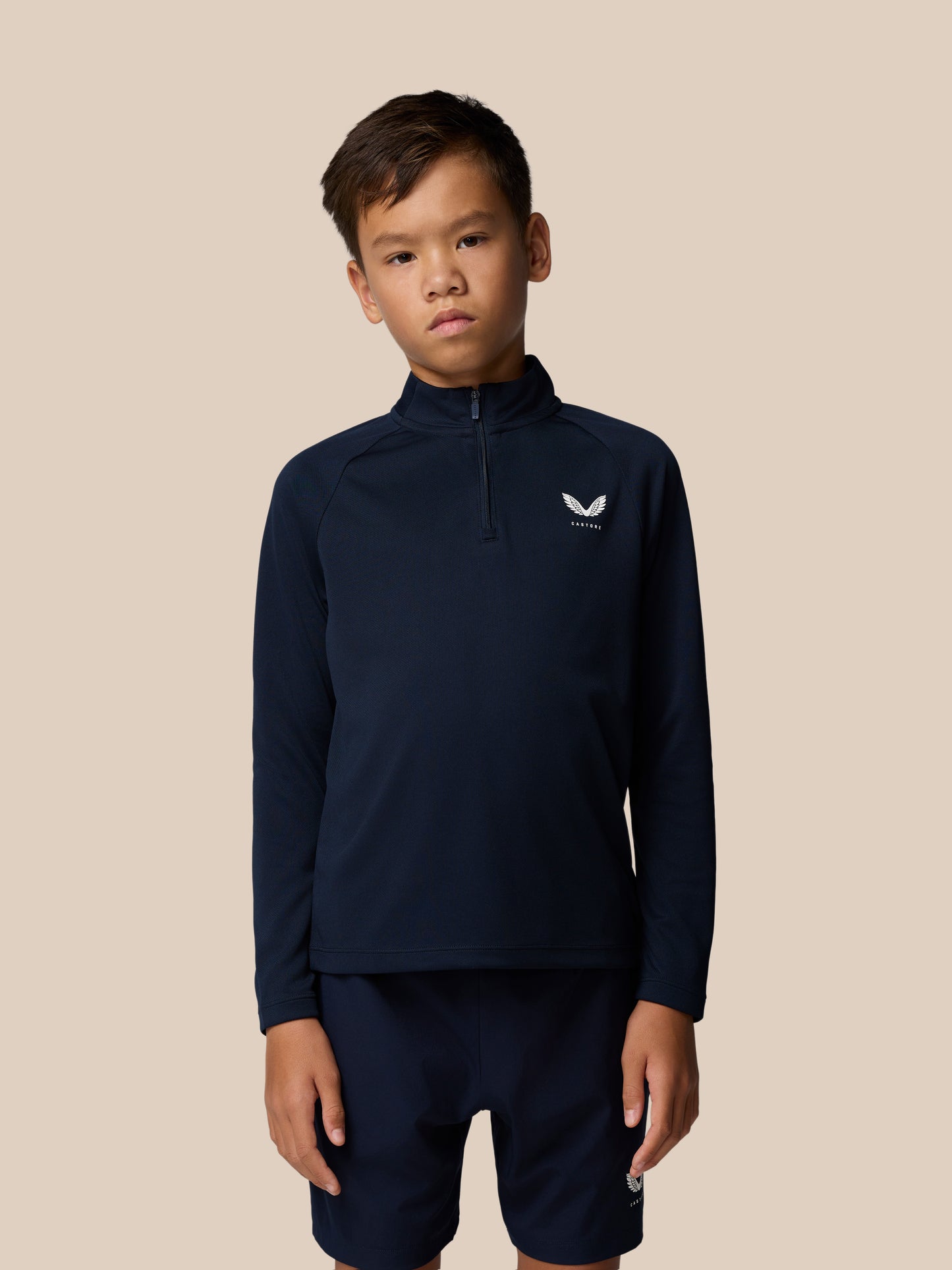 Front view of a young boy wearing navy Adapt Lightweight Quarter Zip with raglan sleeves and a center front zip with a left chest logo