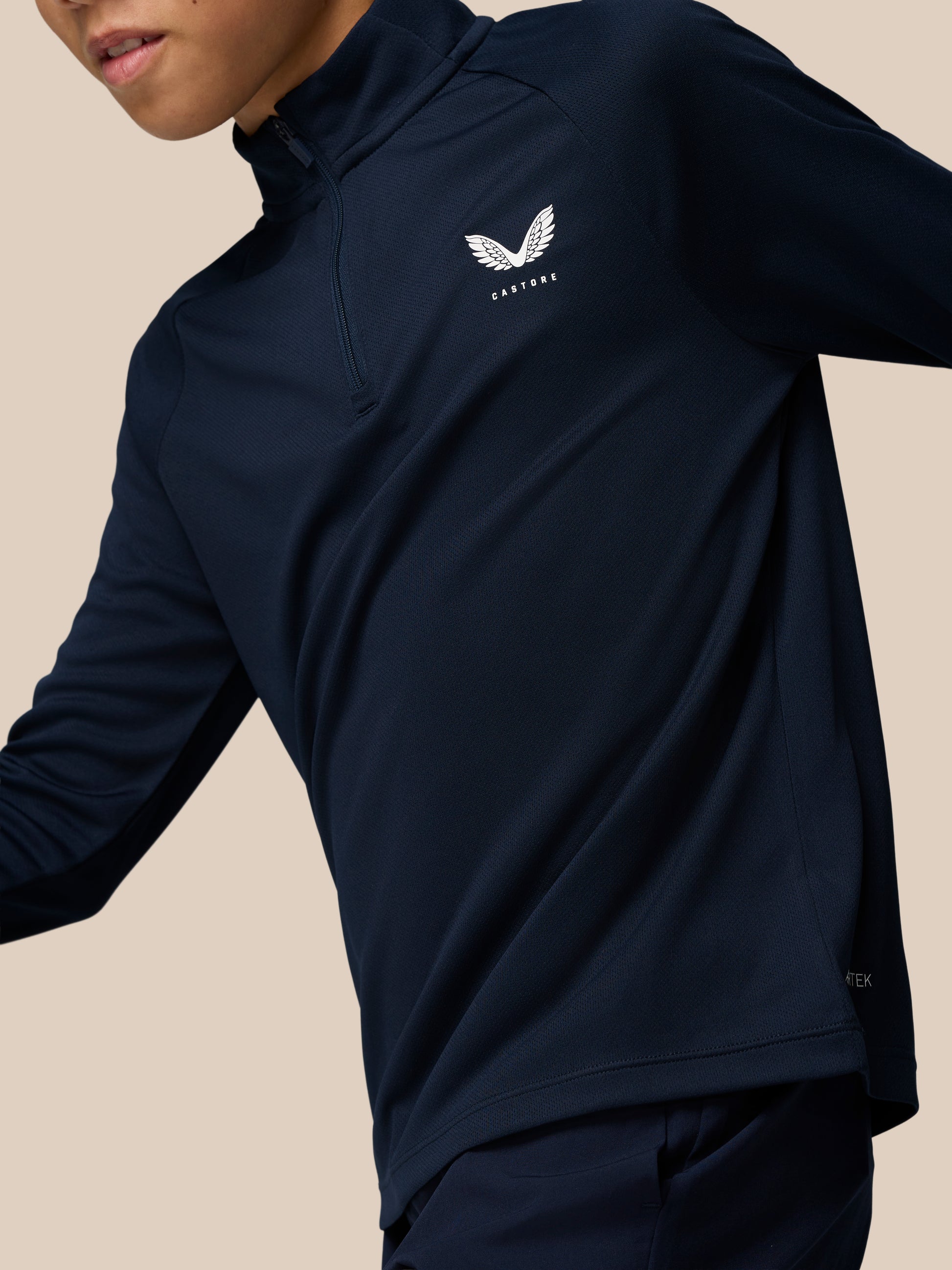 Navy junior athletic quarter-zip top with front zipper and white Castore wing logo on the chest