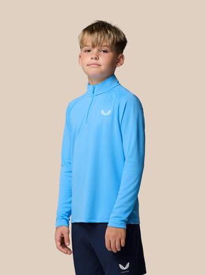 Young boy wearing a light blue Adapt training quarter-zip top with raglan sleeves and Castore branding on chest.