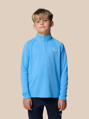 Young boy wearing a light blue quarter-zip athletic top with a small logo on the left chest.