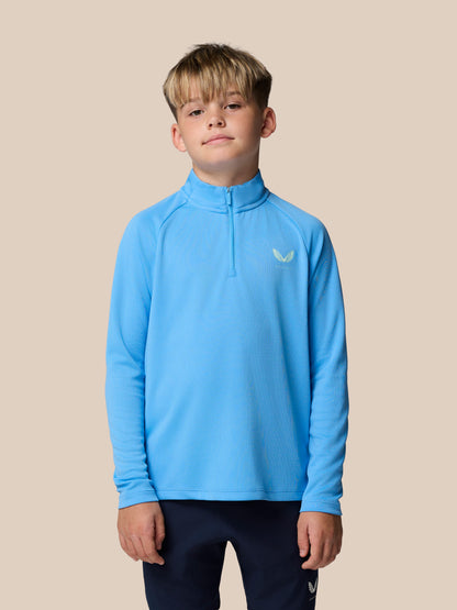 Young boy wearing a light blue quarter-zip athletic top with a small logo on the left chest.