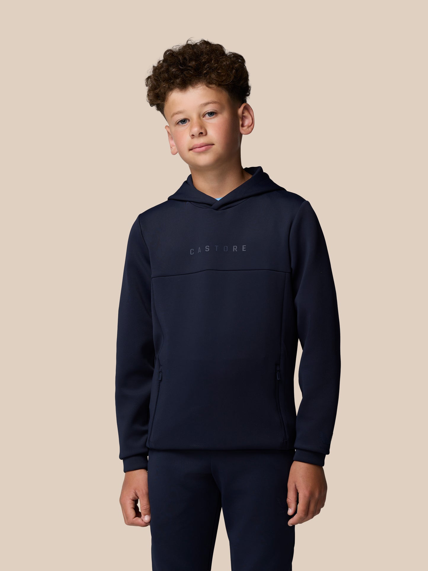 Boy wearing navy Junior Flex Scuba hoodie with hood up and Castore branding on chest.