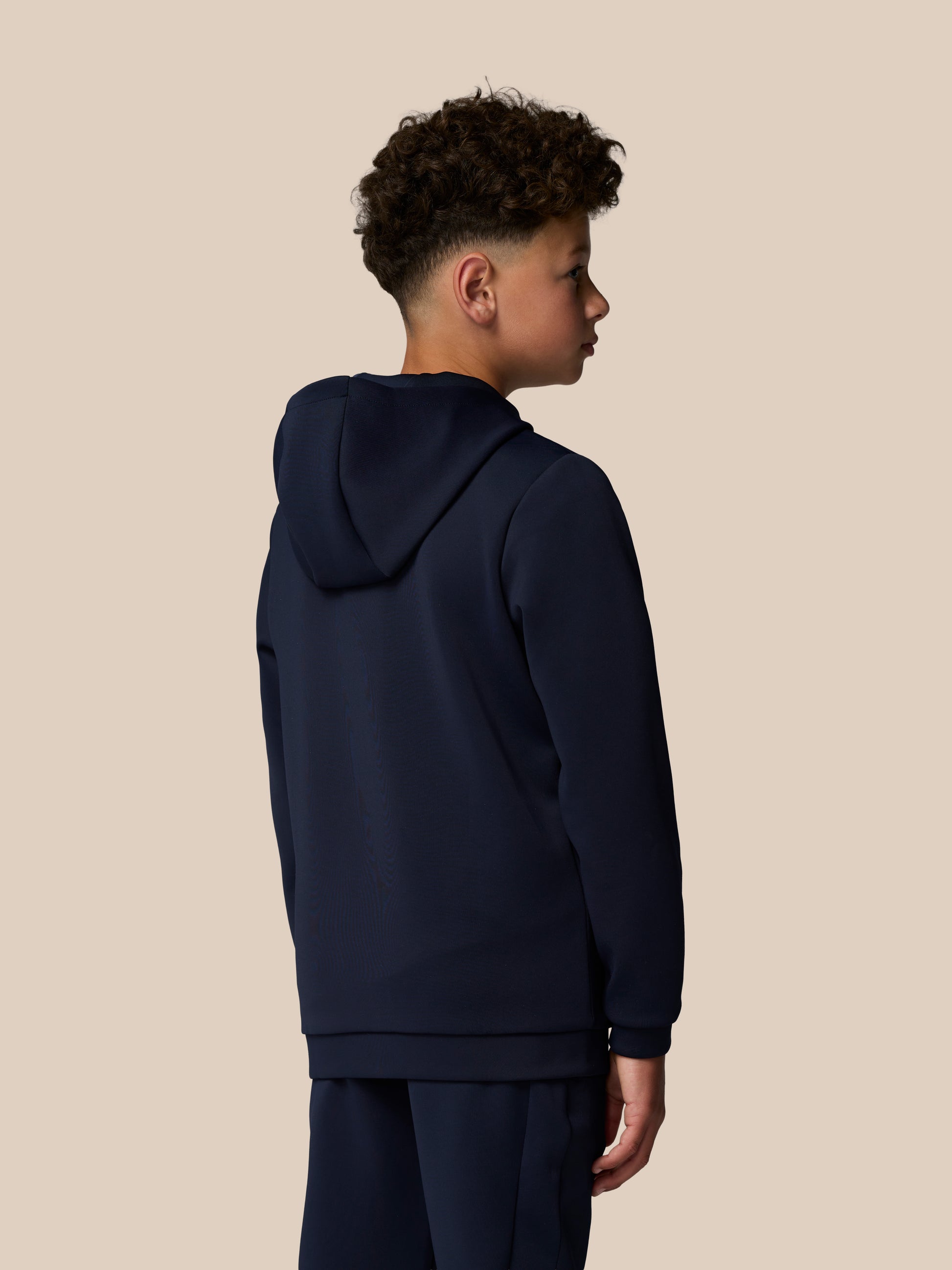 Back and side view of a navy Junior’s Flex Scuba Long Sleeve Hoodie on a young model with hood down