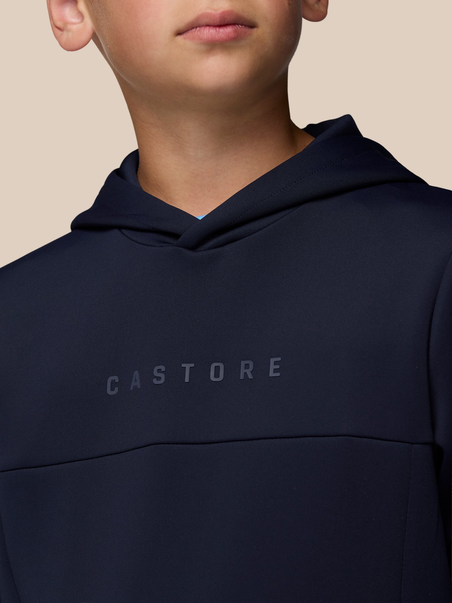Close-up of navy junior hoodie showing hood and the CASTORE branding across the chest