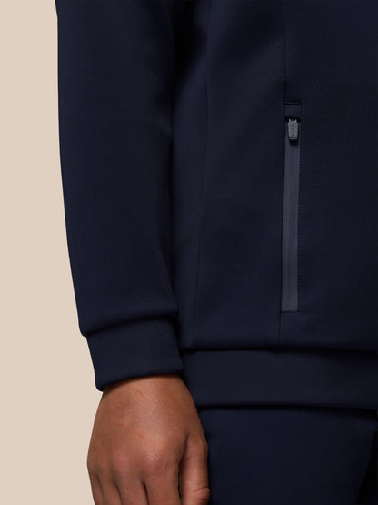 Close-up of navy scuba hoodie fabric with a vertical side zip pocket and a branded zipper pull