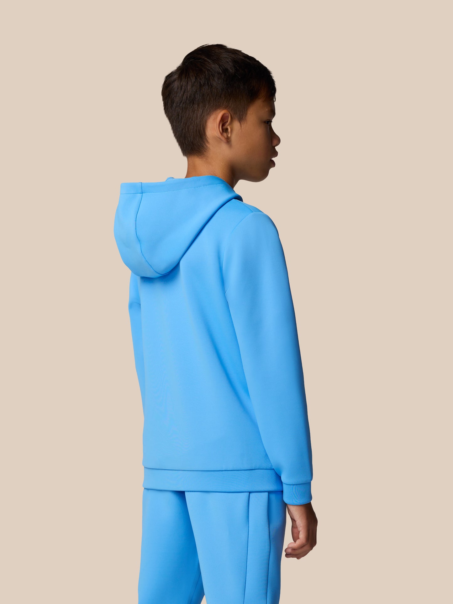 Side profile of a young model wearing a bright blue hoodie from the Junior's Flex Scuba collection.