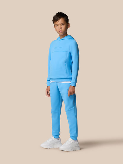 Boy wearing Cool Blue Junior’s Flex Scuba hoodie with Castore logo on the chest and zip pockets
