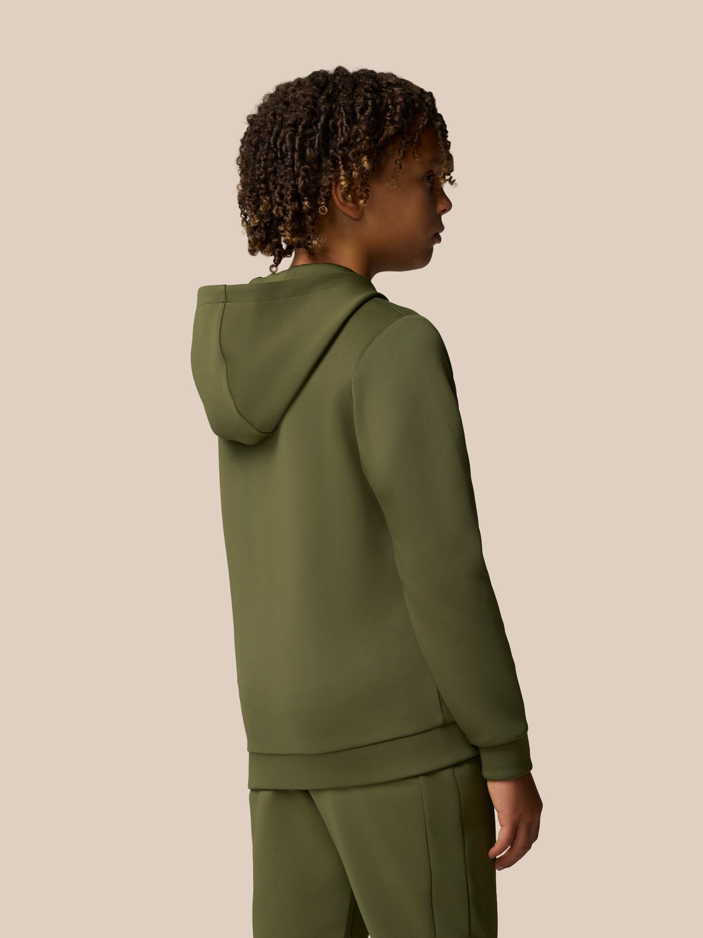 Side profile of a young model wearing an olive green Flex Scuba hoodie with hood down.
