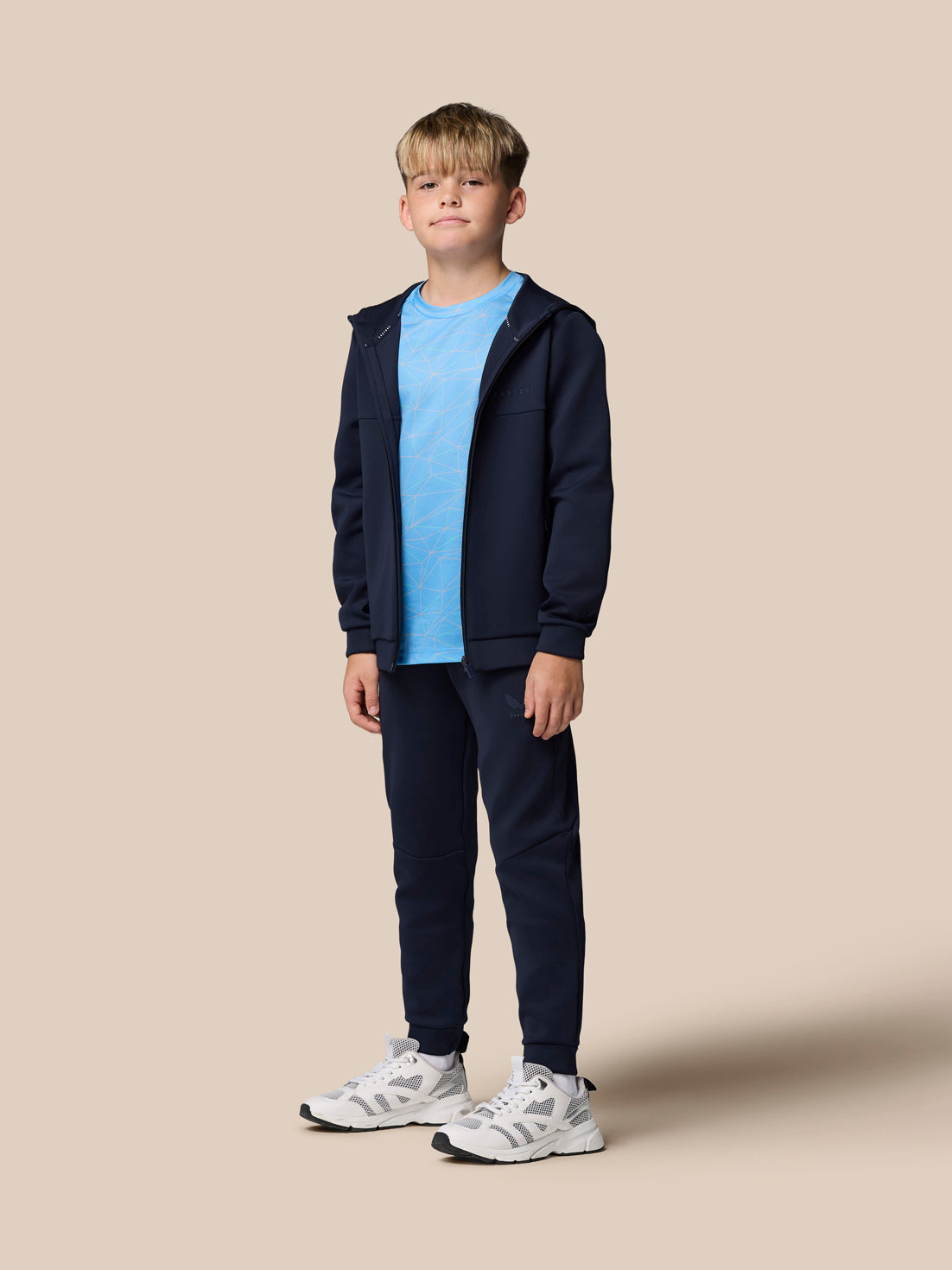 Boy wearing navy Flex scuba jacket fully zipped over a light blue geometric tee with navy joggers and white sneakers