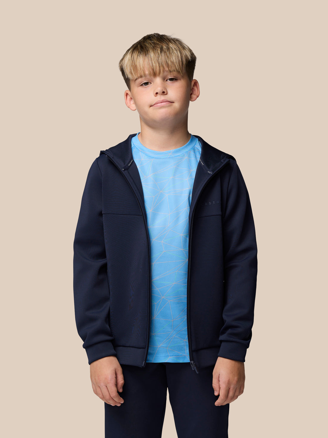 Boy modeling navy Flex scuba jacket unzipped with blue geometric tee visible, navy joggers, white sneakers