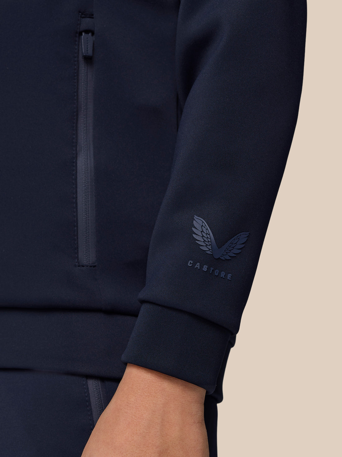 Close-up of navy jacket sleeve with Castore emblem near the cuff