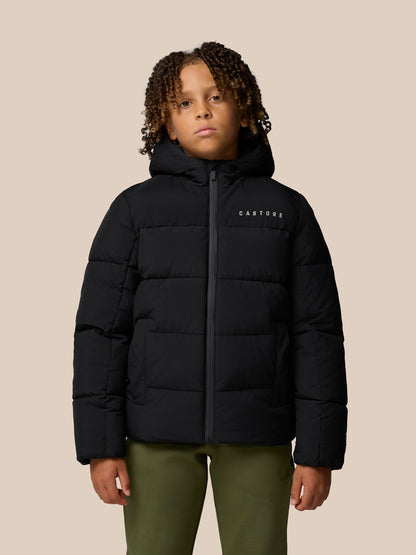 Child wearing black Quilts puffer jacket with hood and front zipper by Castore against a beige background