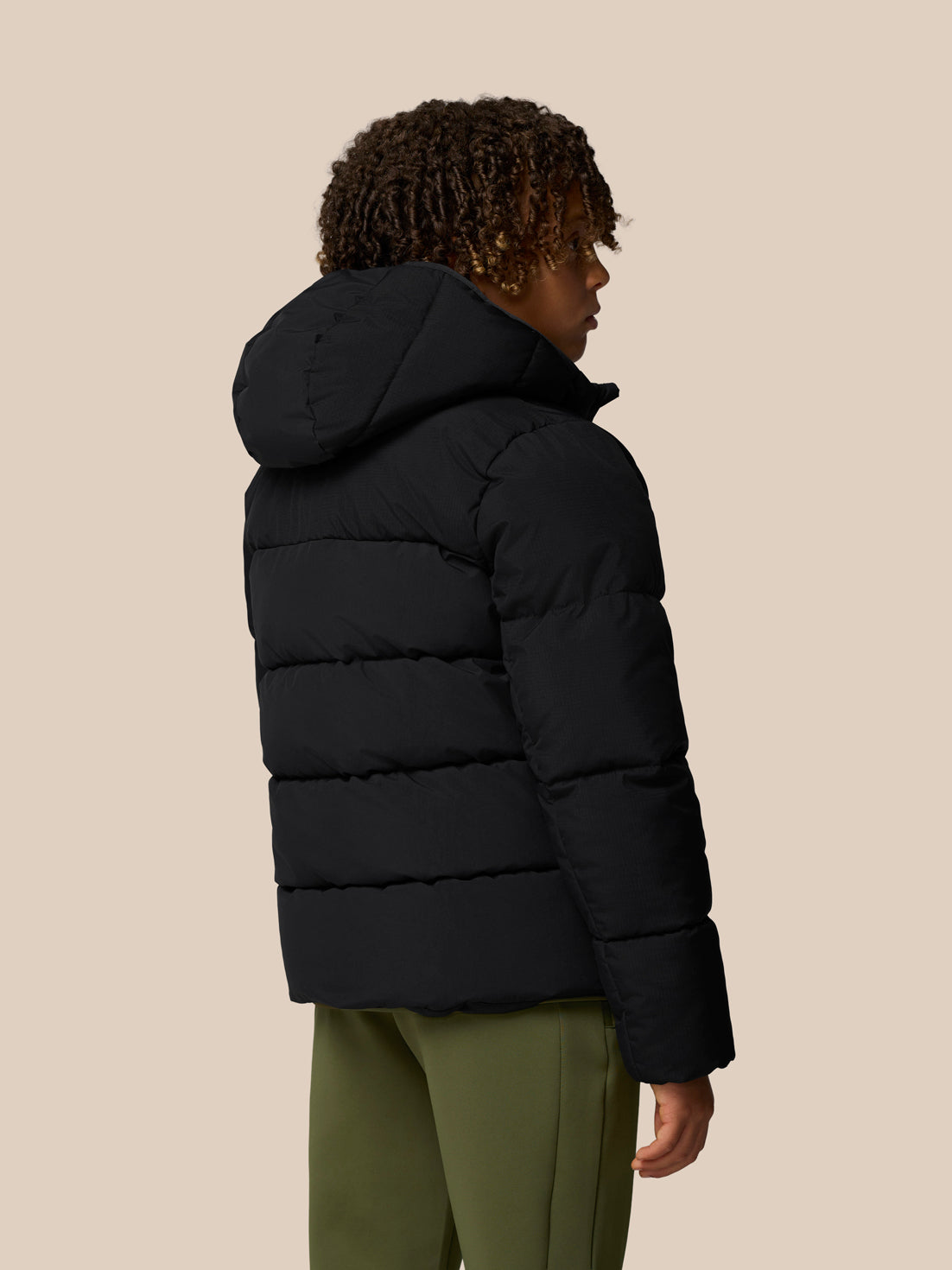 Back view of child in black Quilts puffer jacket with hood showing quilted panels