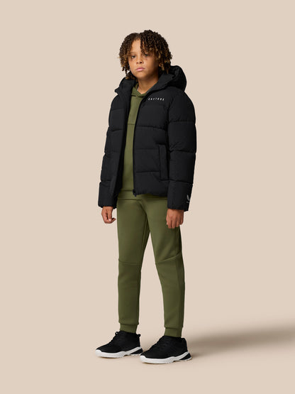 Profile view of child wearing black hooded Quilts puffer jacket with olive green pants