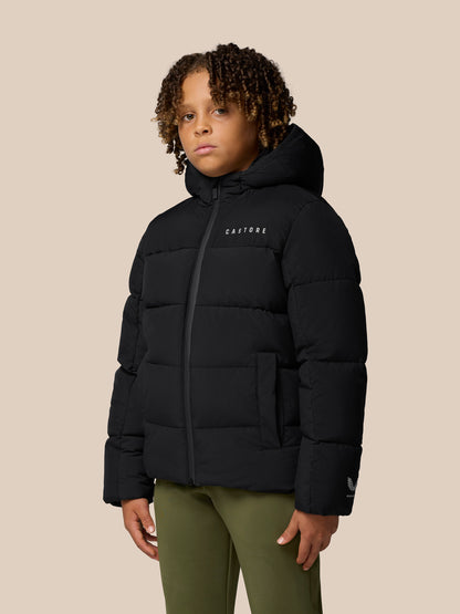 Child model wearing black Castore Quilts Puffer Jacket with hood, front zip and quilted panels.