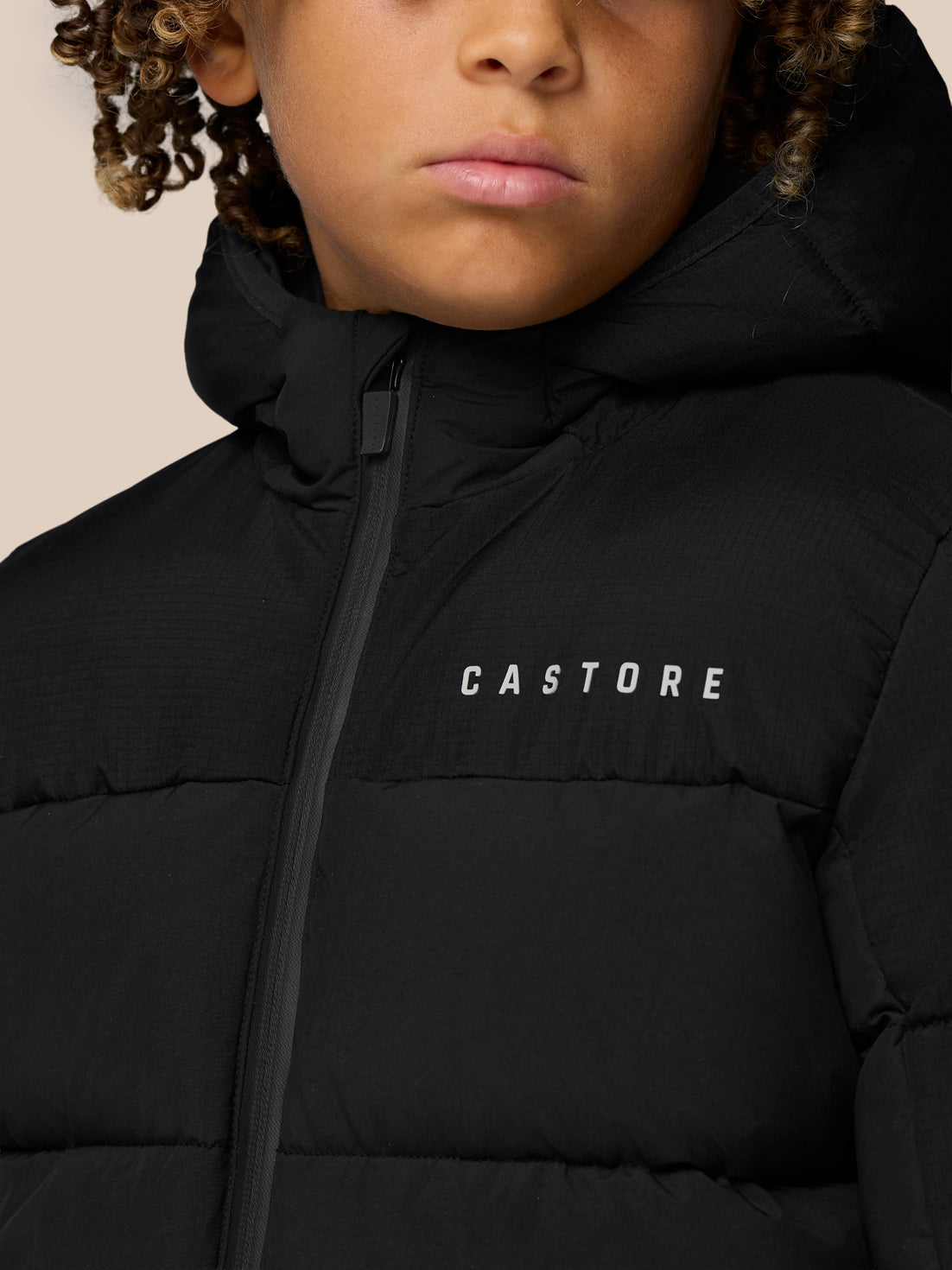 Close-up of a child wearing a black Quilts puffer jacket with hood and CASTORE logo on the chest