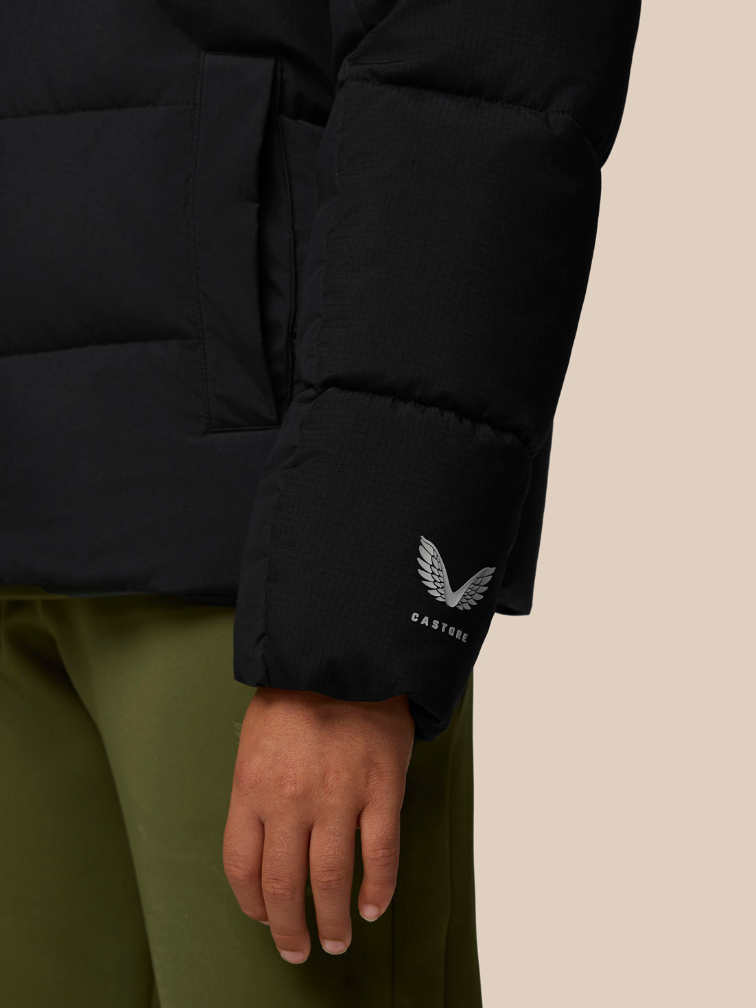 Close-up of a black Quilts puffer jacket sleeve with the Castore wing logo near the cuff