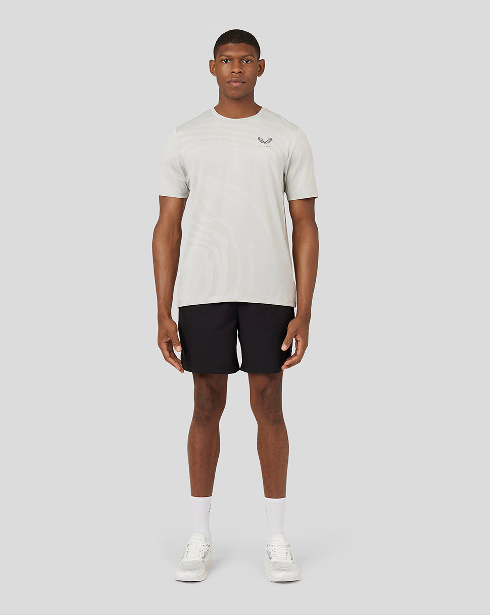 Full body view of a male model in an oyster Core Tech T-Shirt with black shorts.