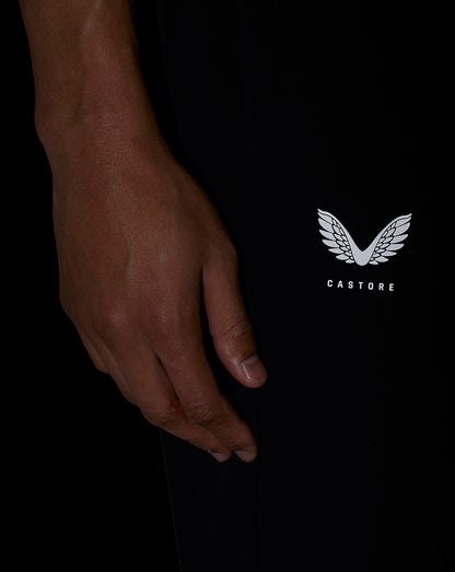 Close-up of a hand beside black woven shorts showing the Castore logo on the leg.