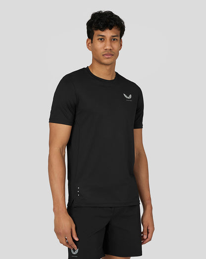 Front view of a man in black Castore performance short sleeve tee with left chest logo and reflective hem details