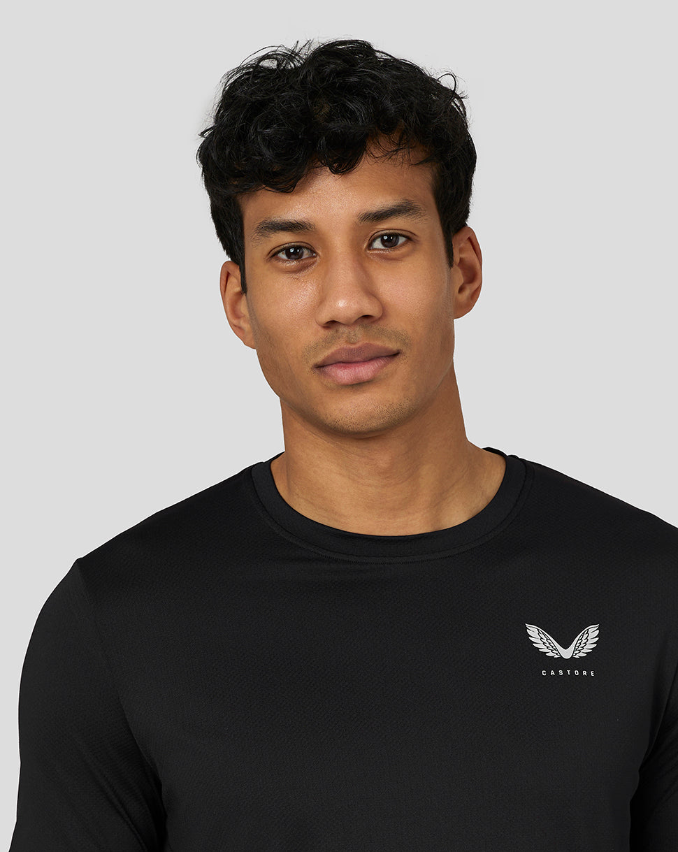 Three quarter front view of a man wearing black Castore performance tee with left chest logo