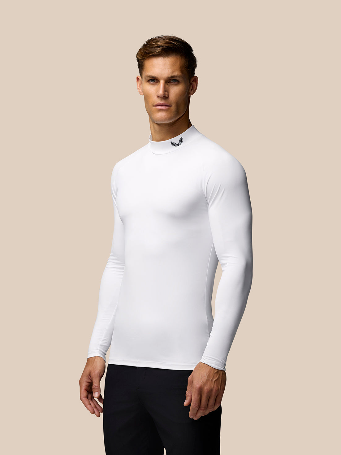 Male model wearing white long sleeve golf base layer with mock neck and Castore logo at the collar