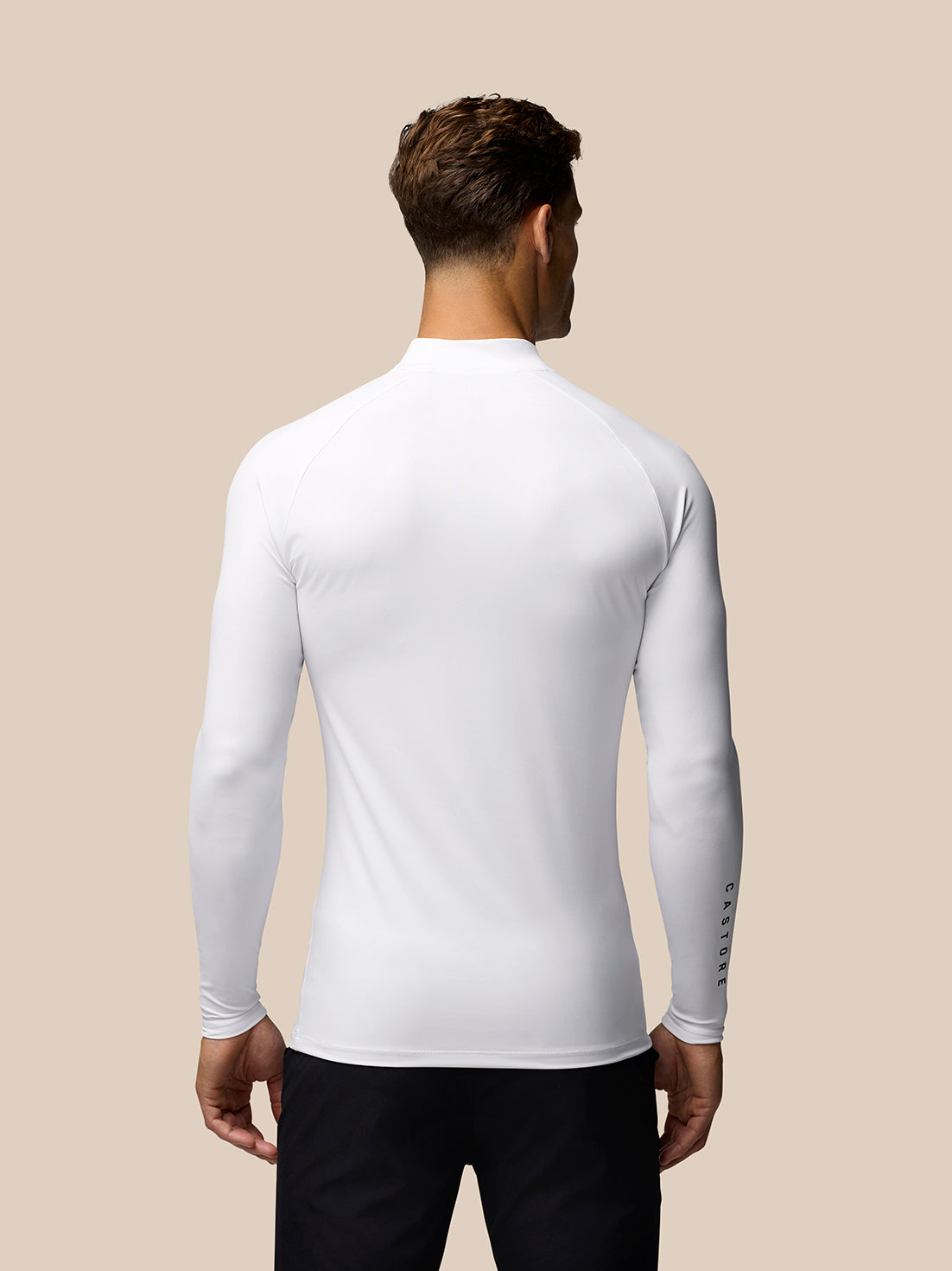 Back view of male model in white long sleeve golf base layer showing Castore branding on the sleeve
