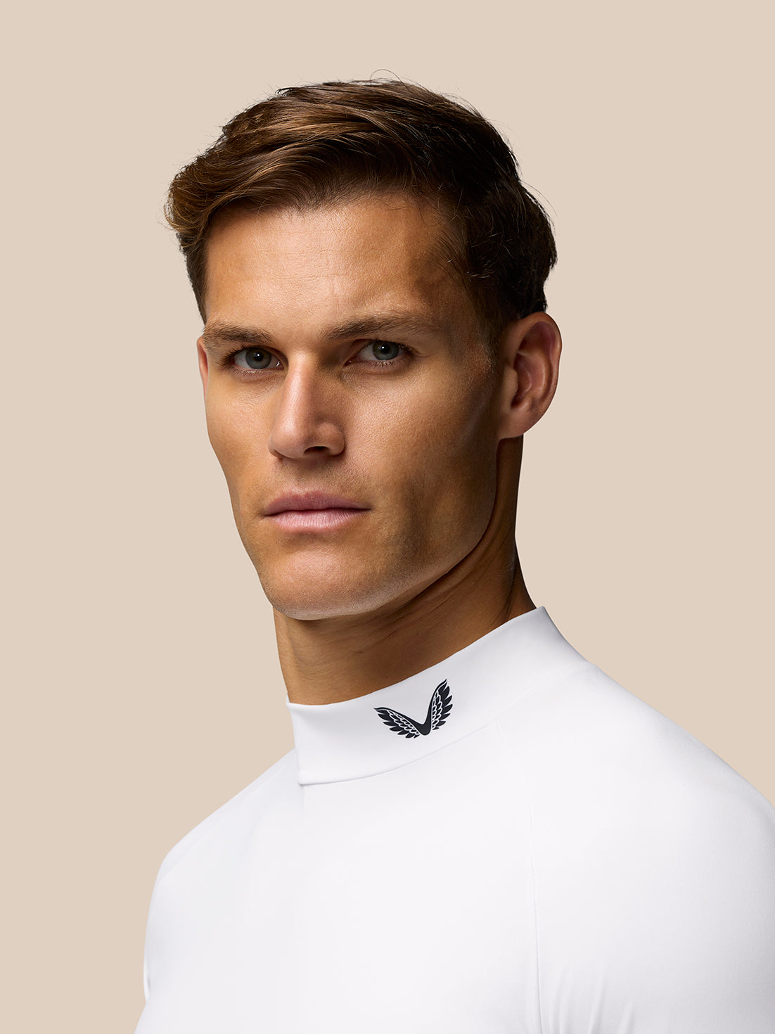 Portrait of a male model in a white mock neck base layer with Castore branding at the collar