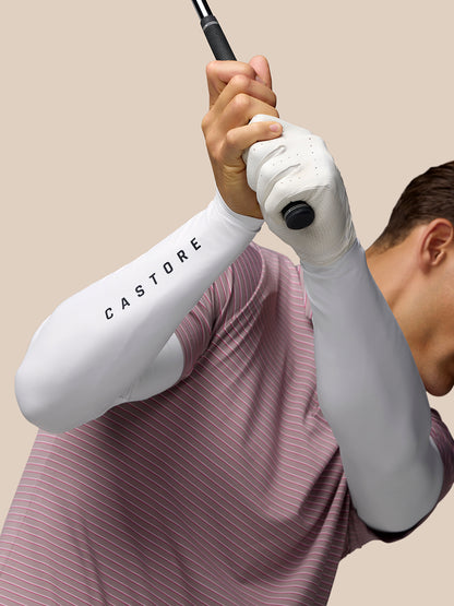 Golfer grips a golf club wearing a white long sleeve base layer with Castore branding on the sleeve