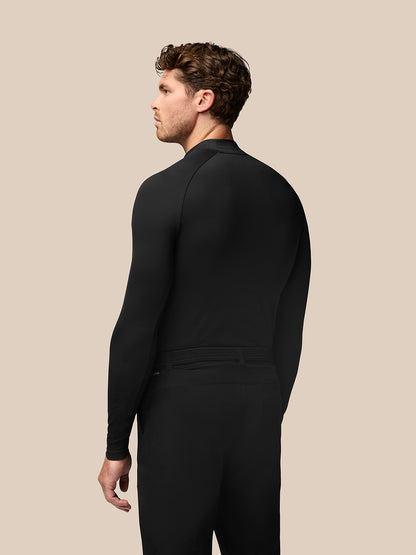 Back view of a man wearing a black golf long sleeve base layer with stand collar and raglan sleeves, Castore branding at the collar.