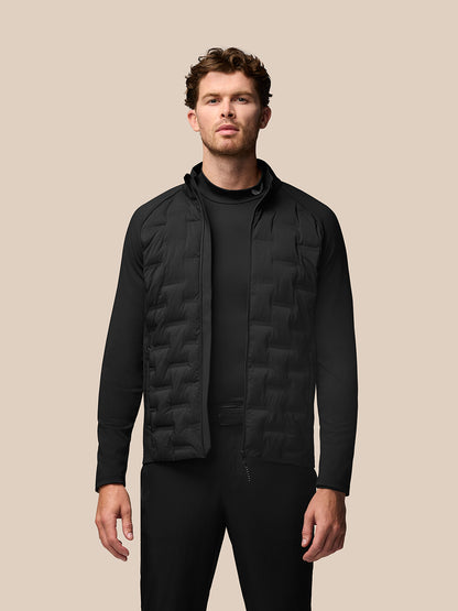 Male model in black golf layering set with a quilted vest over a base layer against a beige background