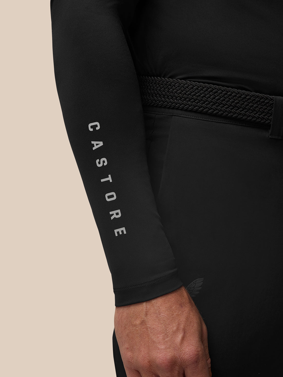 Close-up of a black golf long sleeve base layer sleeve showing Castore branding along the forearm.
