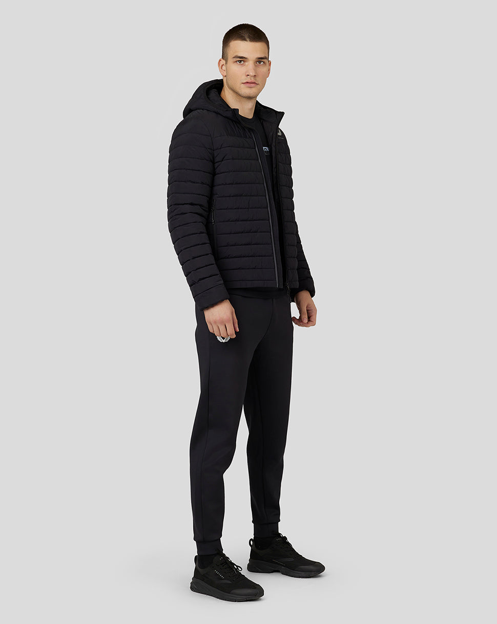 Full body shot of man in black hooded puffer jacket with hood down and zip front