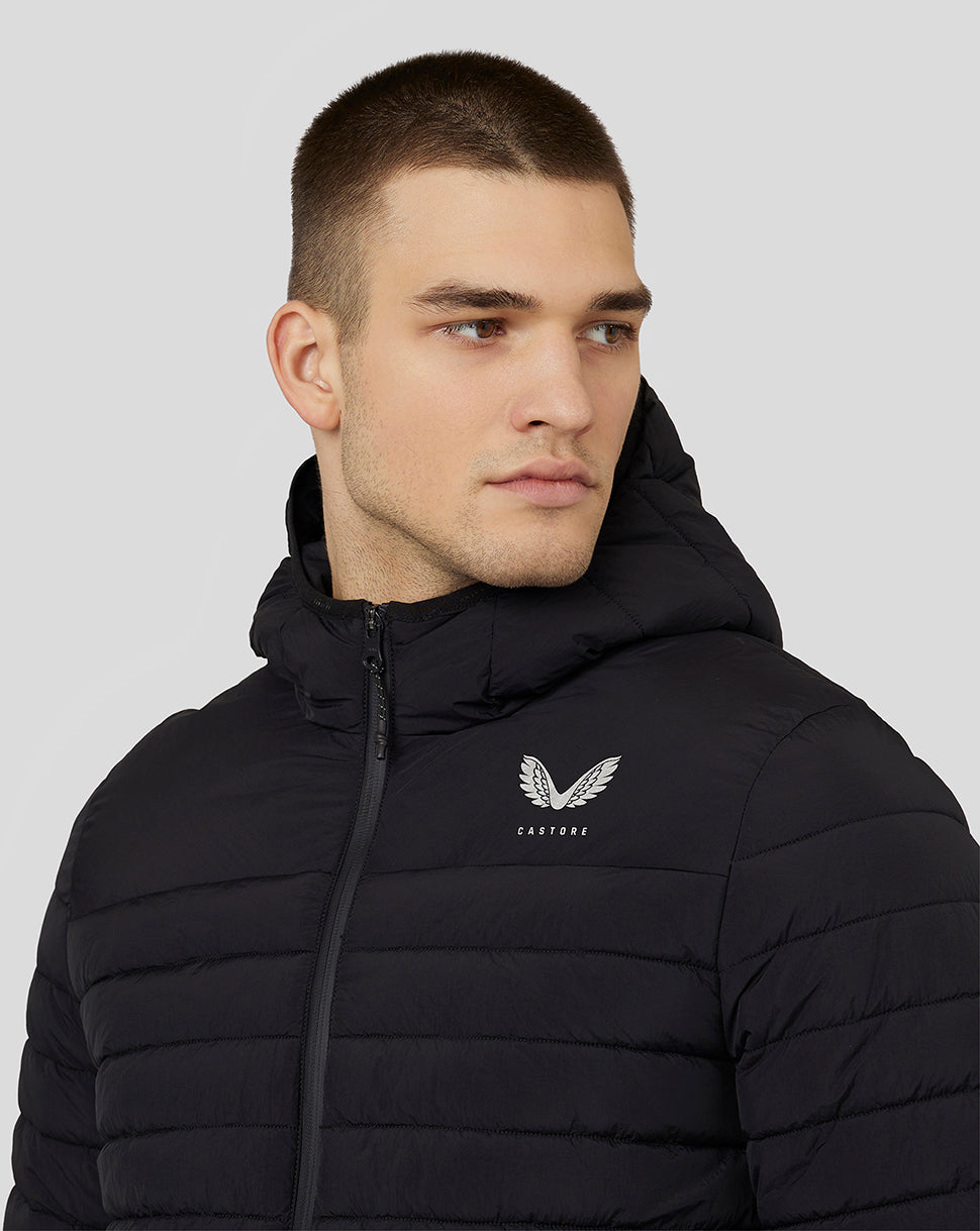 Man wearing black hooded puffer jacket with padded panels and Castore logo on left chest