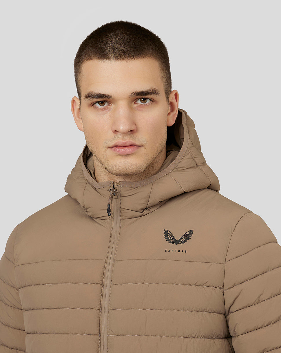 Close up of a man wearing a mushroom colored hooded puffer jacket with Castore logo on the chest