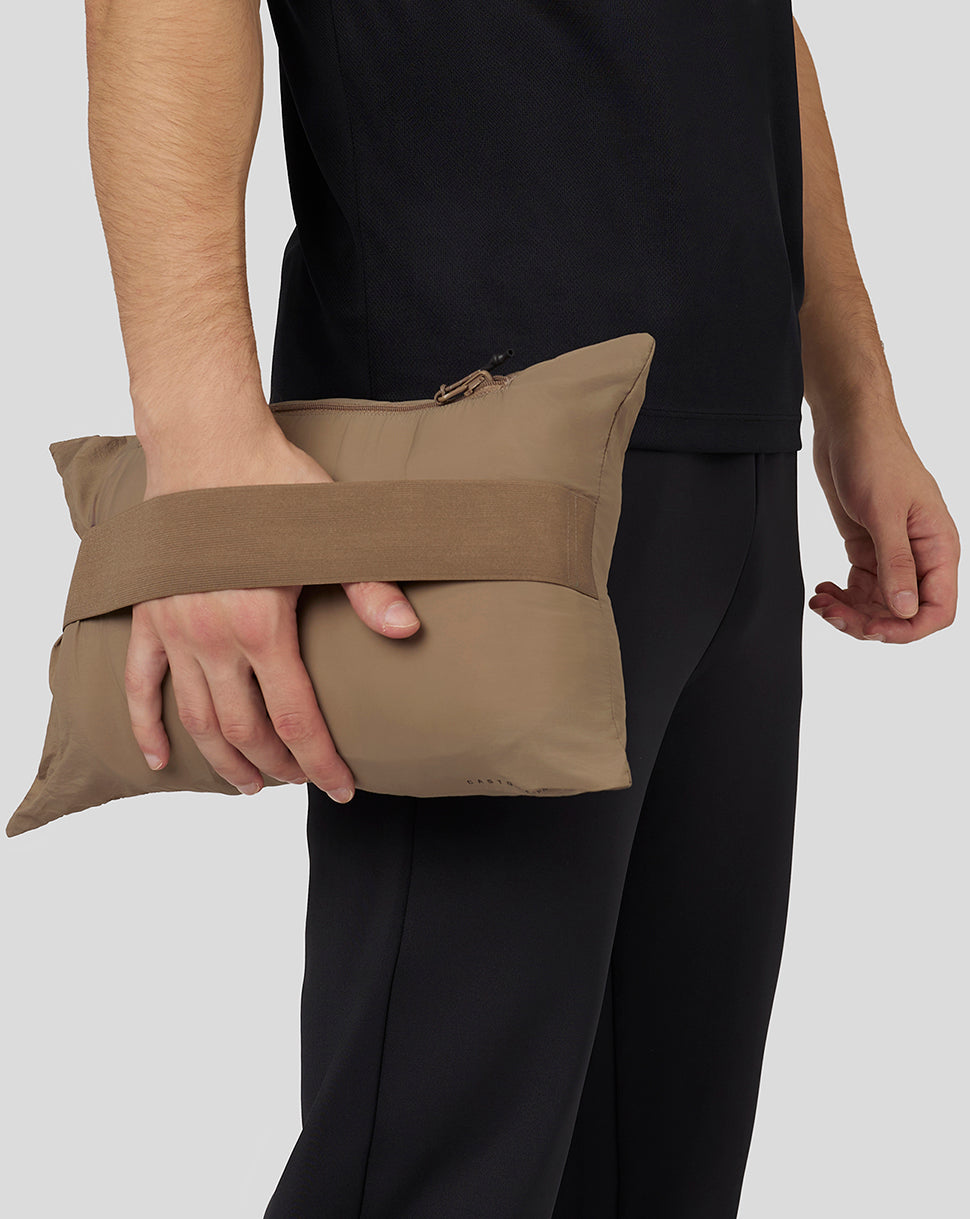 Person holding a beige packable pouch of the jacket to illustrate compressibility