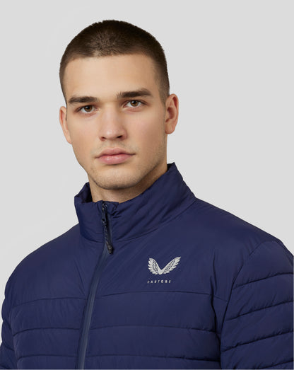 Close-up of a man wearing a navy Castore travel puffer jacket with front zipper and wing emblem